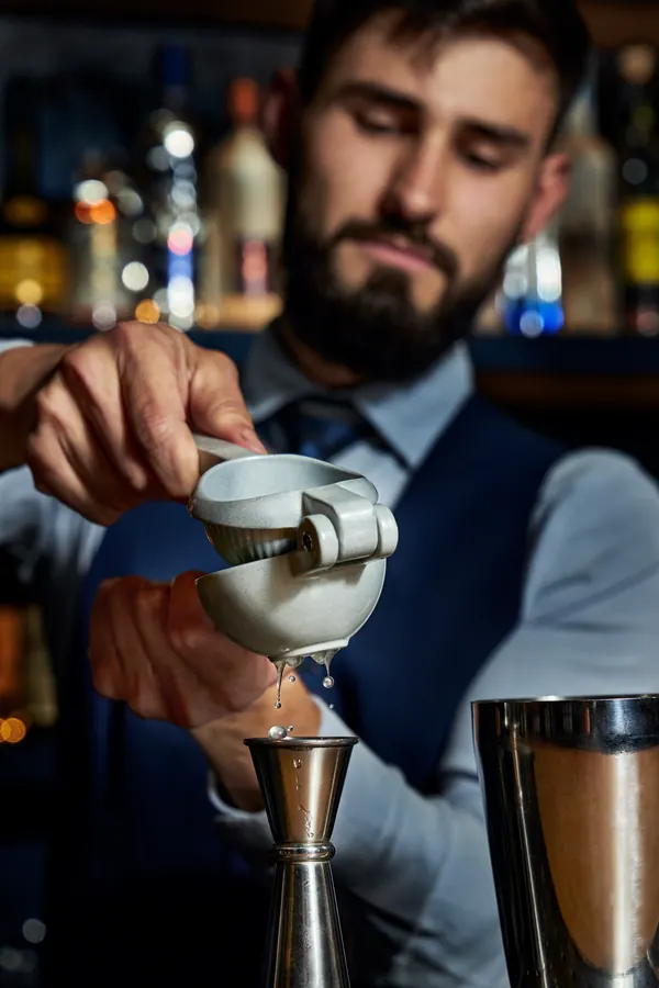 Bartender exprime un cítrico sobre el medidor