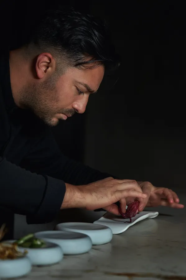 Chef emplatando una línea de platillos sobre mármol