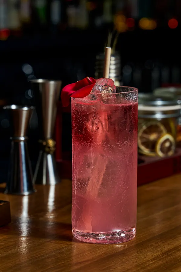 Cóctel rosa en vaso alto con hielo