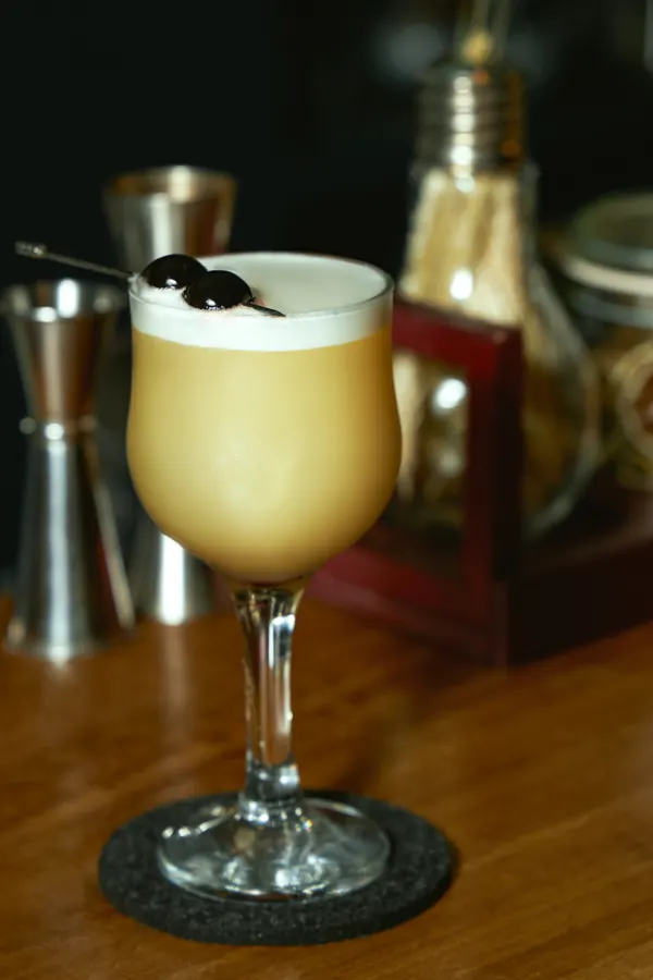 Cóctel sour con espuma y cerezas en la barra