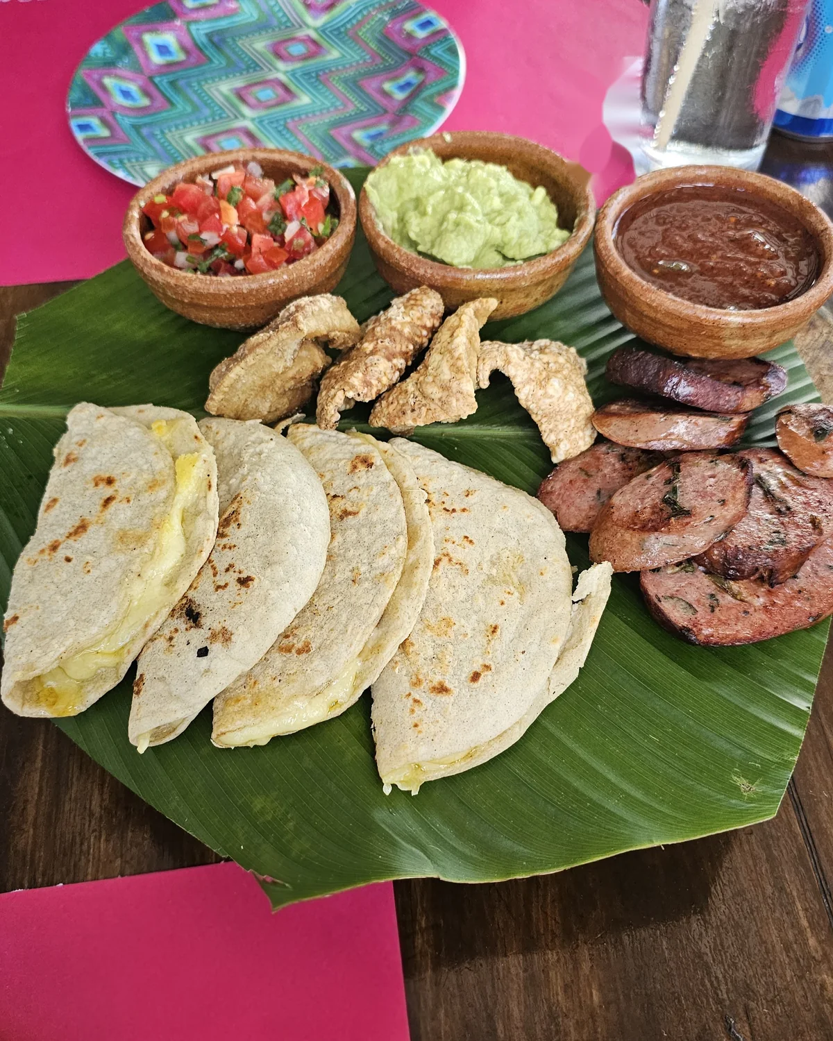 Antes: quesadillas, chicharrón y longaniza sobre hoja de plátano, foto de móvil en la mesa del restaurante