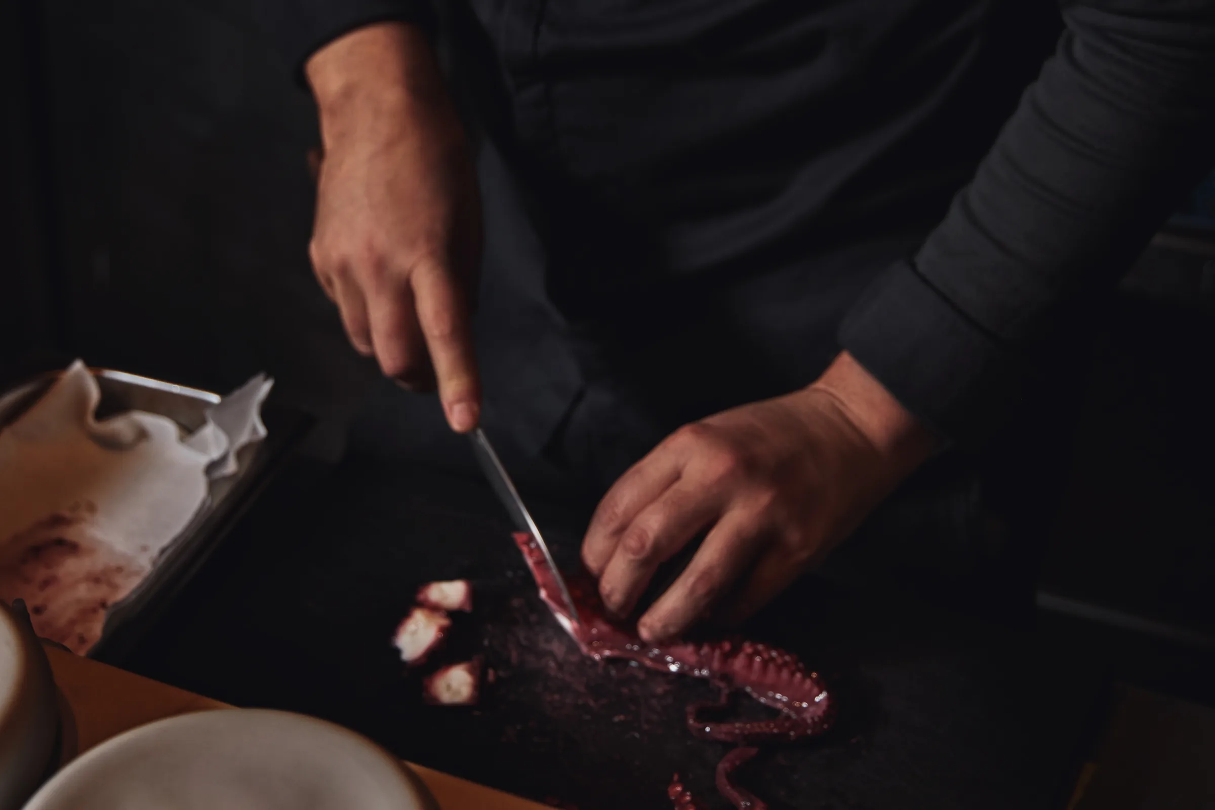 Manos del chef cortando pulpo en la cocina